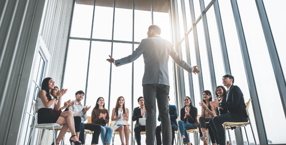 businessman delivering motivating speech to clapping audience